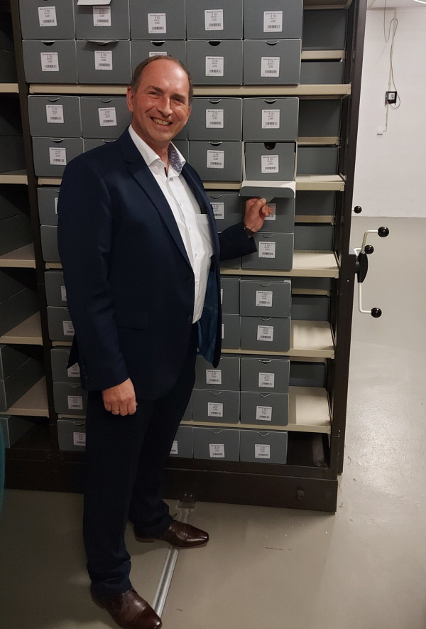 Archivleiter vor Archivregalen