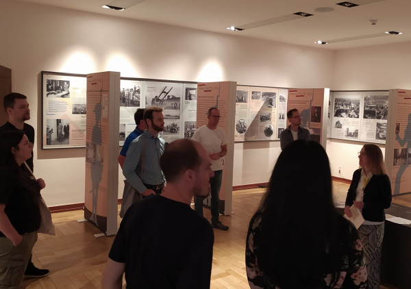Personen stehen in einem Raum mit Ausstellungstafeln